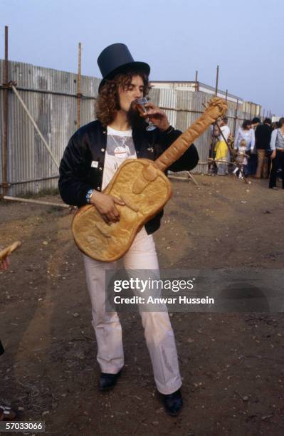 Scottish singer and comedian Billy Connolly, with a guitar apparently made of bread, at 'The Picnic' concert at Blackbushe Aerodrome on July 15, 1978...