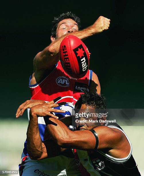 Rohan Smith for the Bulldogs punches the ball clear of Xavier Clarke for the Saints during the NAB Challenge match between the St Kilda Saints and...