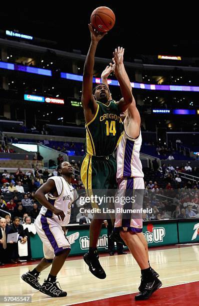 Brandon Lincoln of the Oregon Ducks puts a shot up over Mike Jensen and Justin Dentmon of the Washington Huskies in the second half of their...