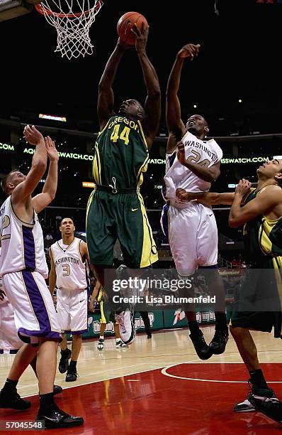 Ivan Johnson of the Oregon Ducks goes to the basket past Mike Jensen and Jamaal Williams of the Washington Huskies in the second half of their...