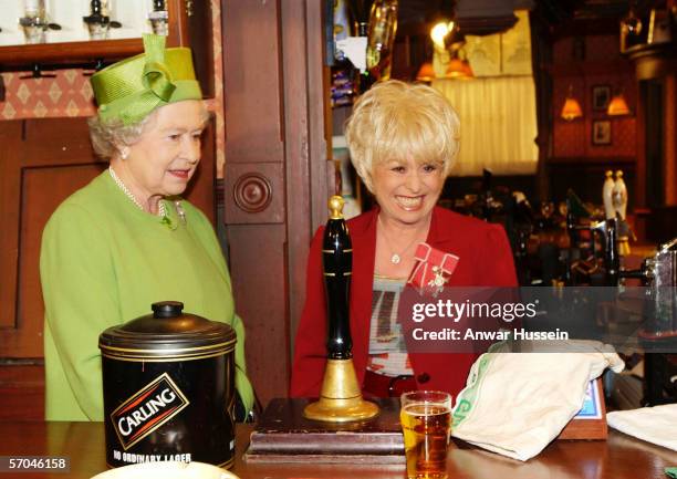 Queen Elizabeth ll visits the set of the soap 'Eastenders"and is shown behind the bar of the "Queen Vic" public house by star Barbara Windsor on...