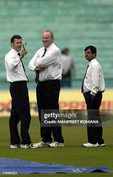 Australian cricket umpire Simon Tuffel is watched by colleague Darrell Hair and an unidentifed match official as he measures the light using a meter...