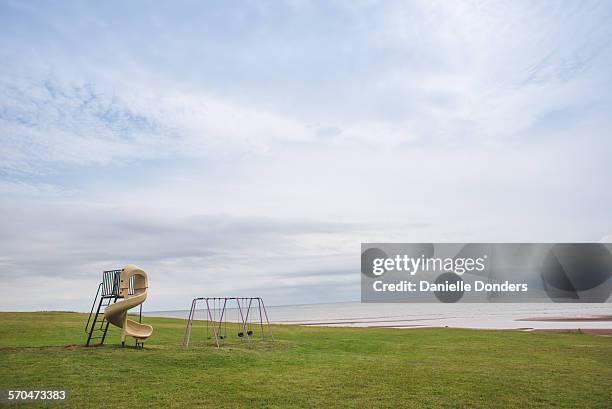 empty swingset and slide at the seashore - abandoned playground stock pictures, royalty-free photos & images