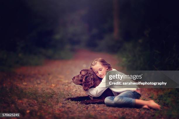 little girl hugging her dog on path - grief loss stock pictures, royalty-free photos & images