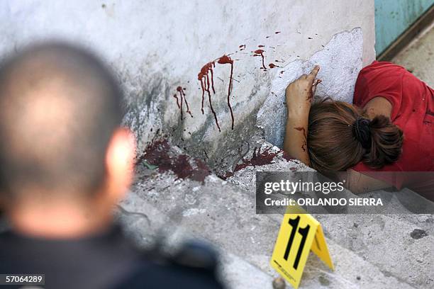 Un agente de la Policia Nacional Civil , observa el cadaver de una mujer que permanece sin vida sobre unas gradas en las inmediaciones del estadio...