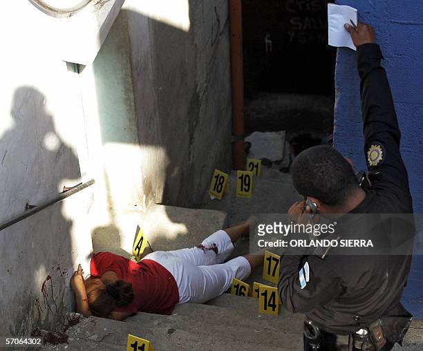 Un agente de la Policia Nacional Civil observa el cadaver de una mujer que permanece sin vida sobre unas gradas en las inmediaciones del estadio...