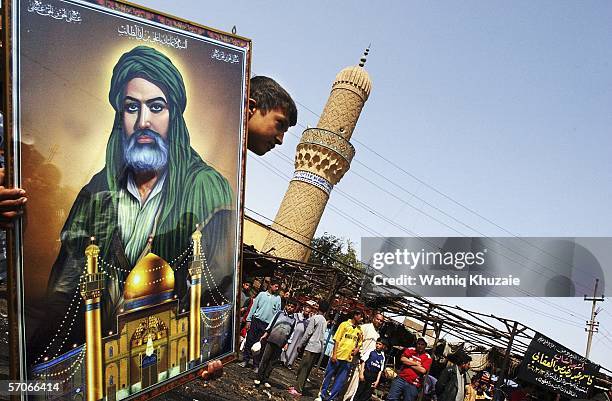 An Iraqi boy carries a picture of Imam Ali at the scene of yesterday's car bomb explosion, in a marketplace March 13, 2006 in the Shiite neighborhood...