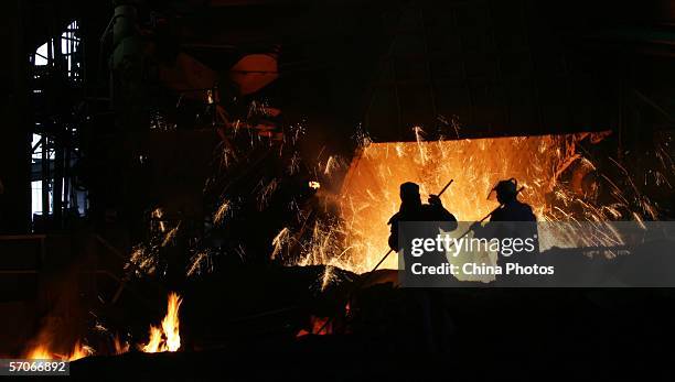 Steelworkers stir material in front of a steel making furnace at the Chongqing Iron and Steel Factory March 13, 2006 in Chongqing Municipality,...