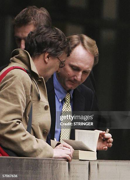 United Kingdom: Best-selling author Dan Brown signs a copy of his book for a fan as he leaves the High Court in London, 13 March 2006. Brown broke...