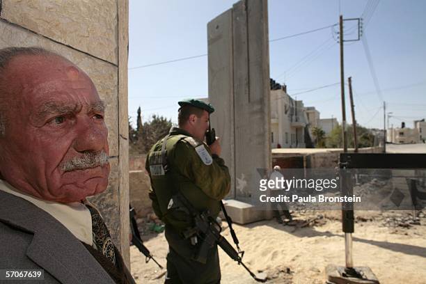 Palestinian man watches new concrete blocks being moved into place at the separation barrier from East Jerusalem to Eizariya on March 13, 2006 in the...