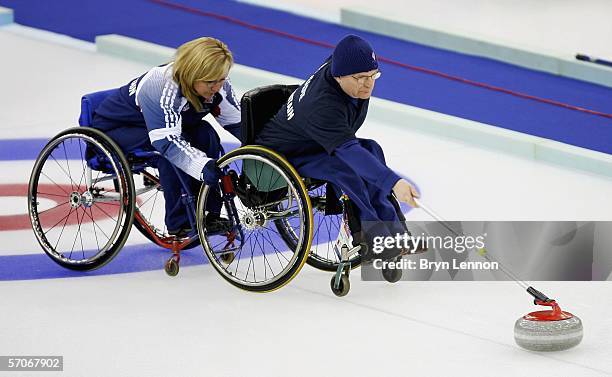 Angie Malone of Great Britain steadies team mate Michael McCreadie as he releases the stone during the Wheelchair Curling match between Great Britain...