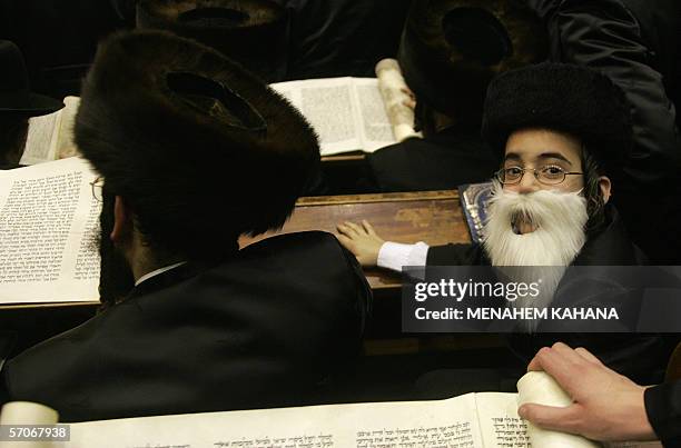 Boy looks over as Ultra Orthodox Jews from the Wiznitz Hassidim group reads the Ester scrolls at the synagogue in the Israeli town of Beni Brak near...