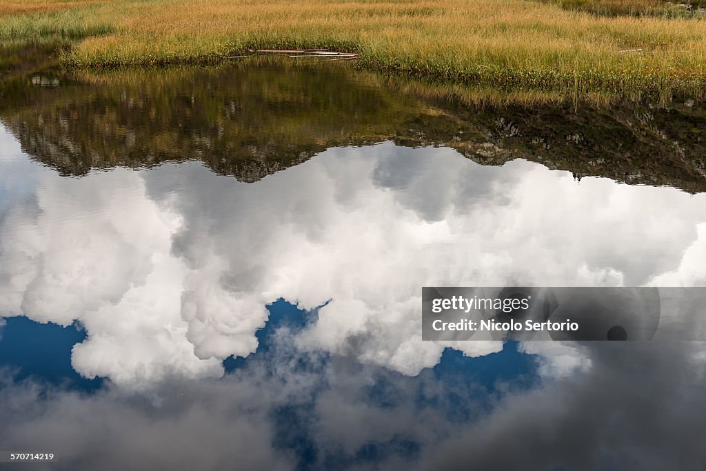 Clouds and mountains reflecting in mountain lake