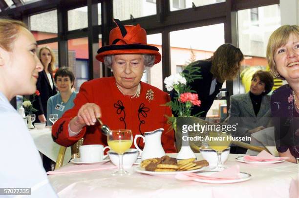 Queen Elizabeth II takes a tea break with hospital staff during her visit to Manchester Royal Infirmary on October 15, 1999.
