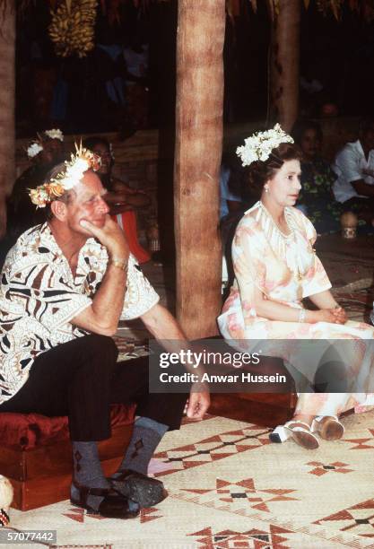 Queen Elizabeth ll and Prince Phillip, Duke of Edinburgh sit with flowers on their heads in Tuvalu in 1982.