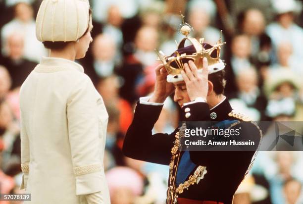 Prince Charles kneels before Queen Elizabeth as she crowns him Prince of Wales at the Investiture at Caernarvon Castle on July 1, 1969 in Wales.