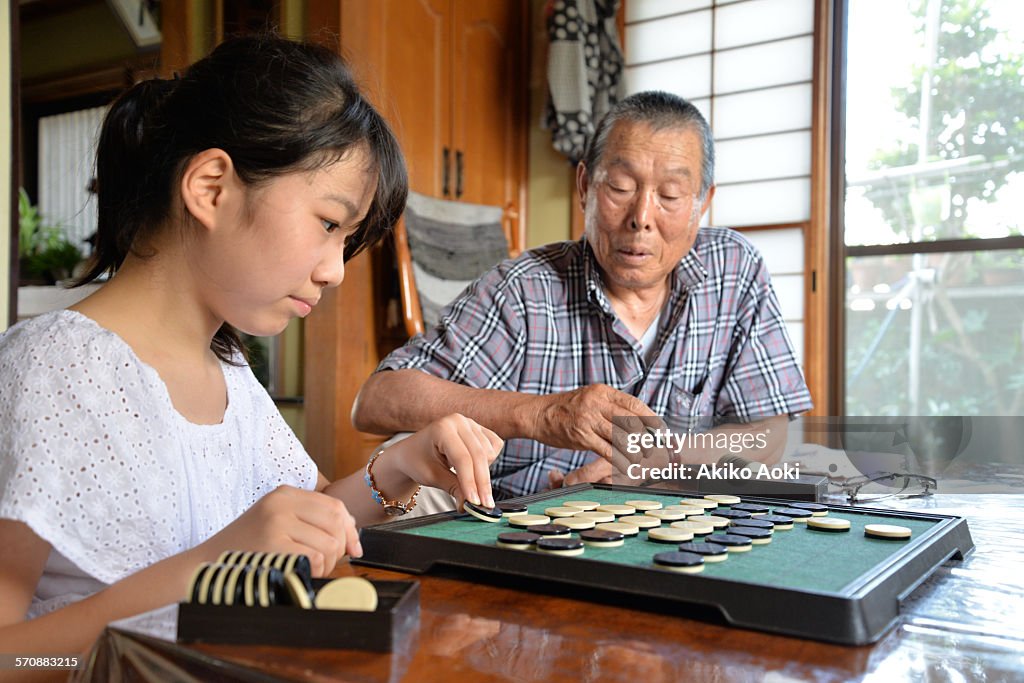 Grandpa and granddaughter playing Othello game.