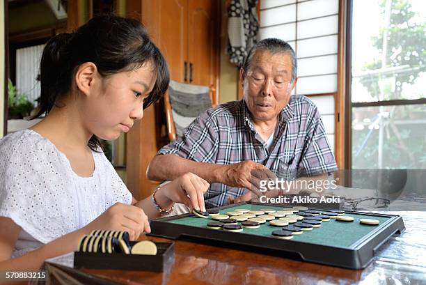 grandpa and granddaughter playing othello game. - othello stock pictures, royalty-free photos & images