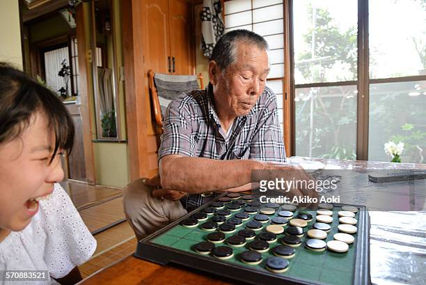 girl and aged man playing othello game. - othello stock pictures, royalty-free photos & images