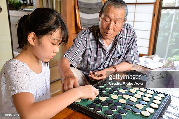 child and aged man playing othello game. - othello stock pictures, royalty-free photos & images