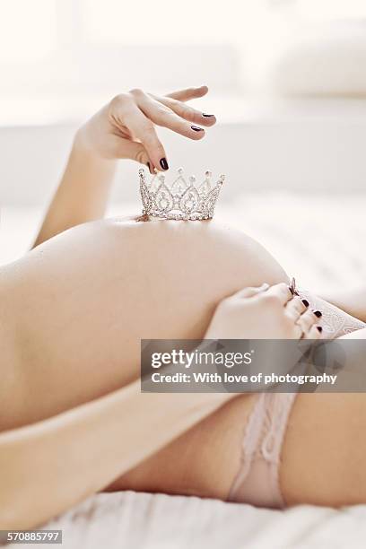 pregnant woman holding a crown on belly - it's a girl stock-fotos und bilder