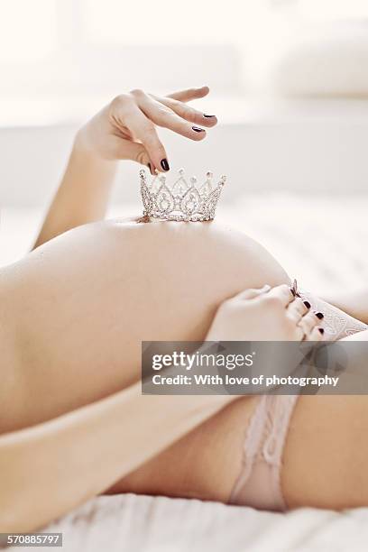 pregnant woman holding a crown on belly - its a girl ストックフォトと画像