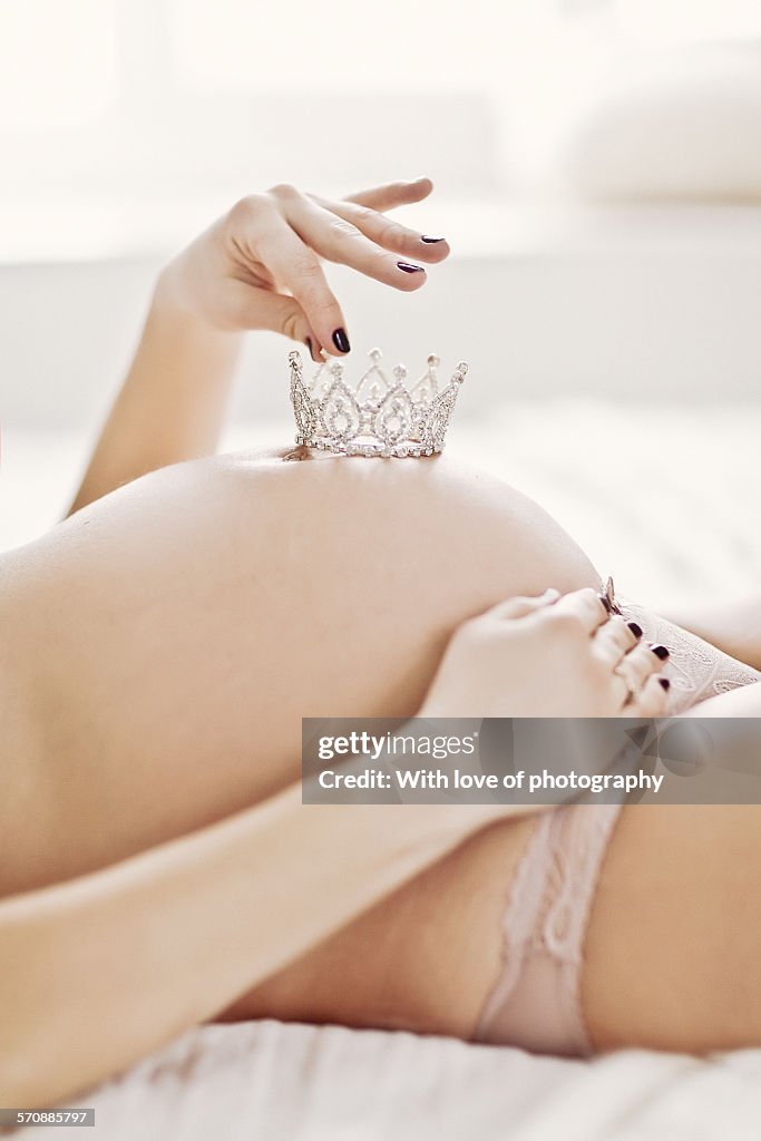 Pregnant woman holding a crown on belly