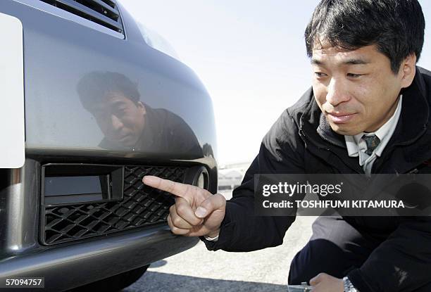 An engineer shows a radar sensor and main controller of the Nissan Motors' new Distance Control Assist System installed under the front bumper of the...