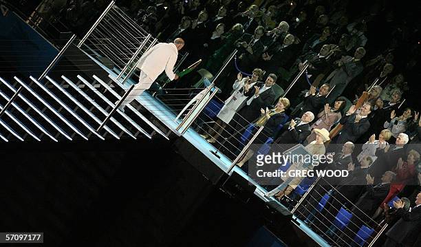 Former Australian Olympic star John Landy climbs the stairs with the Queen's Baton to present it to Queen Elizabeth II during the opening ceremony...