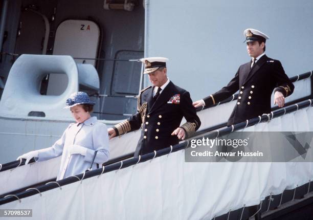 Queen Elizabeth II and Prince Philip, the Duke of Edinburgh walk down the gangway of HMS Invincible after welcoming back the Duke of York from the...