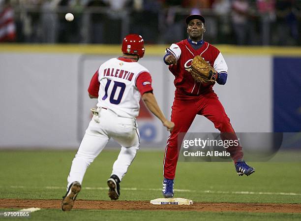 Eduardo Paret of Cuba throws to complete a double play to end the eighth inning as Jose Valentin of Puerto Rico looks to slide during Round 2 of the...