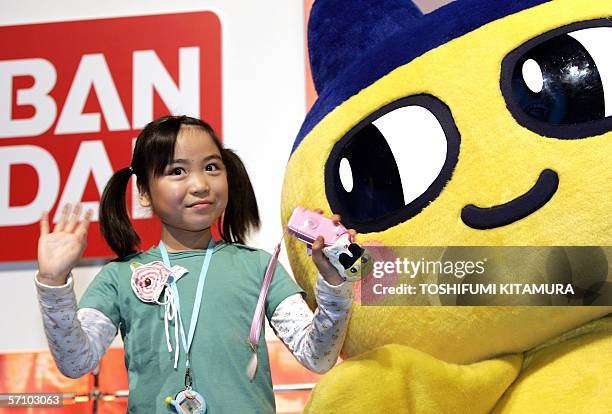 Girl presents Japanese toy maker Bandai's latest PHS handset for children, "Kids Keitai papipo" beside the company's Tamagotch charactor during its...