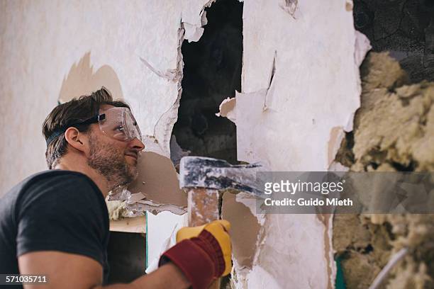 man doing demolition. - casser mur photos et images de collection