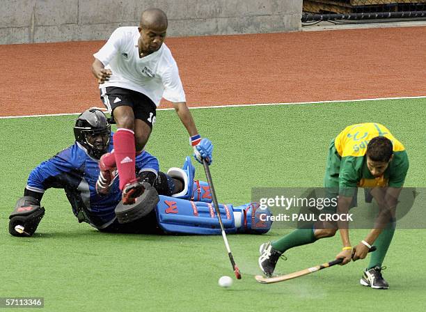 South Africa forward Leroy Phillips smashes the ball past Trinidad and Tobago defenders during their men's field hockey preliminary match at the...