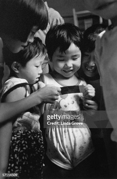 Children from the Yellow Mountain region of China are amused by a Polaroid photograph, 1996. One of them is wearing a Mickey Mouse vest.