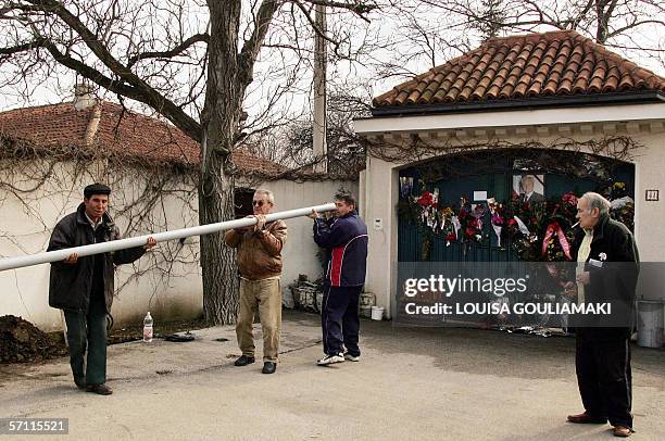 Pozarevac, SERBIA AND MONTENEGRO: Workers carry a mast for a flag to place it in front of the gate of late Yugoslav leader Slobodan Milosevic's...