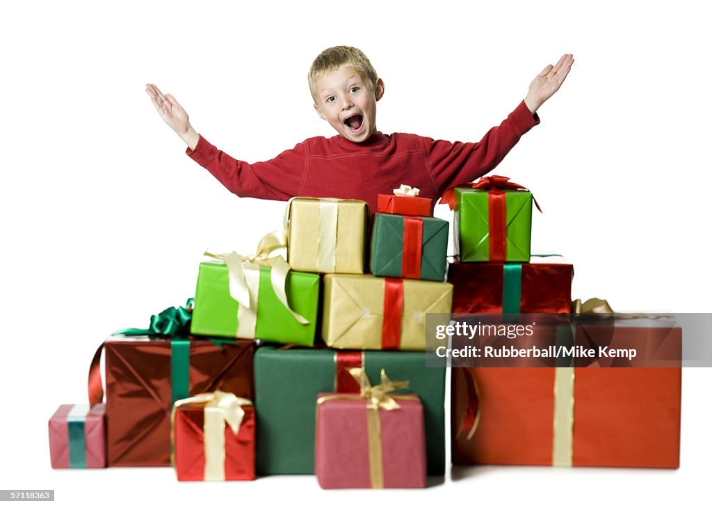 Portrait of a boy standing with his arms raised with gifts around him