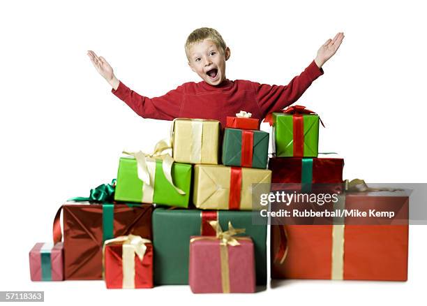 Portrait Of A Boy Standing With His Arms Raised With Gifts Around Him, Foto de stock