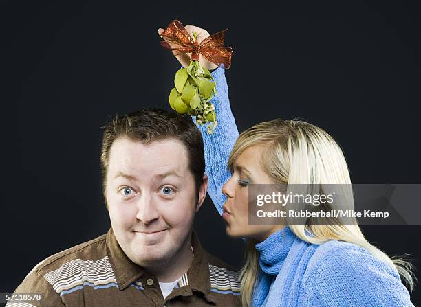 close-up of a young woman holding a mistletoe over the head of a young man - man with tape on lips stock pictures, royalty-free photos & images