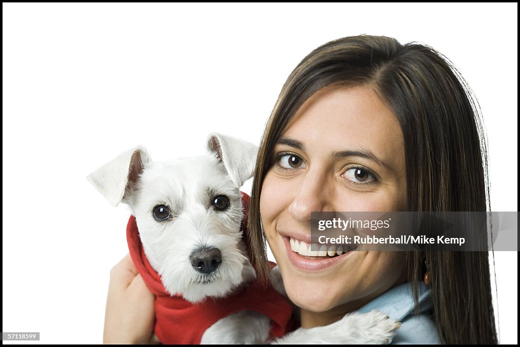 Portrait of a young woman holding a dog in her arms and smiling