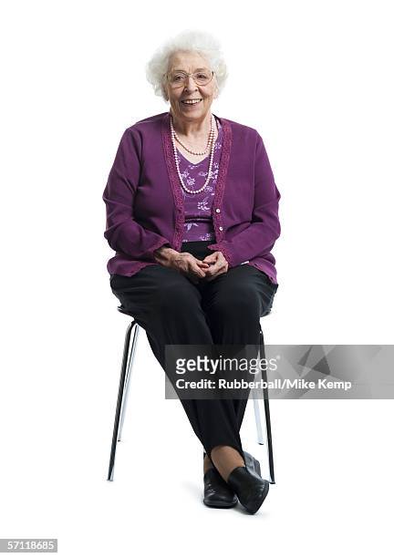 portrait of a senior woman sitting on a chair - old woman sitting stock-fotos und bilder