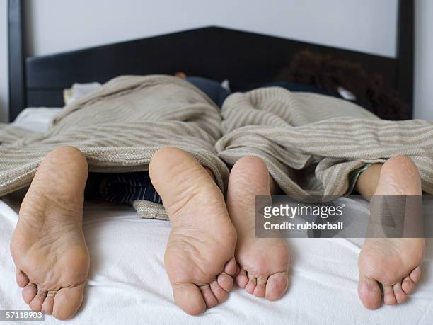 close-up of a couple's feet in bed - woman lying on stomach with feet up fotografías e imágenes de stock