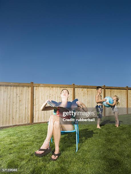 brother and sister playing with a beach ball while their mother suntans - reflector fotografías e imágenes de stock