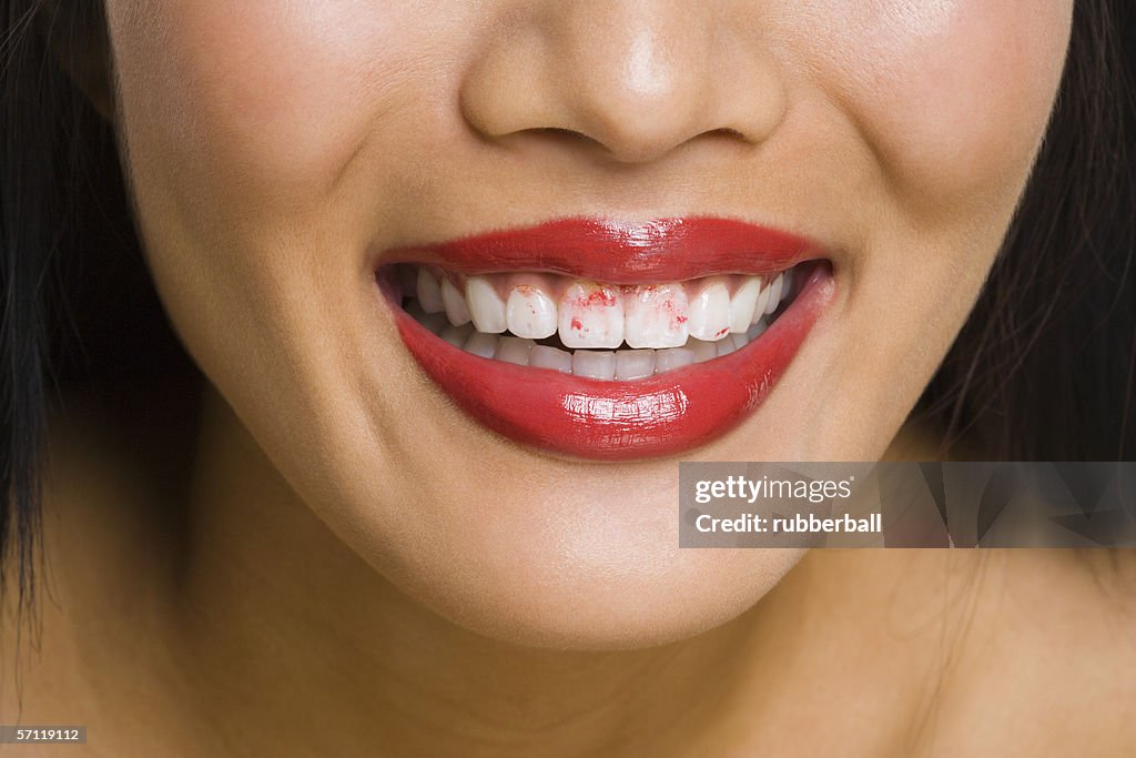 Close-up of a woman's lips with lipstick on her teeth