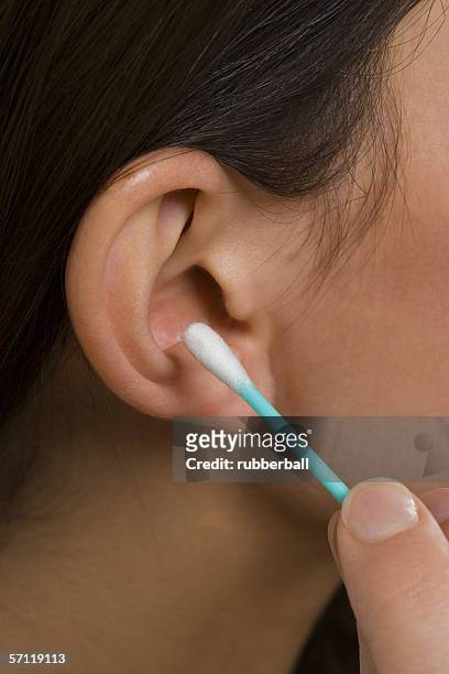 close-up of a woman cleaning her ear with a cotton swab - woman fingers in ears stock pictures, royalty-free photos & images