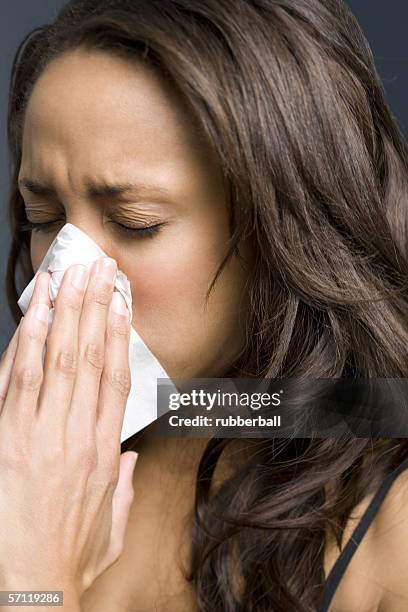 close-up of a young woman blowing her nose - closeup of a hispanic woman sneezing foto e immagini stock