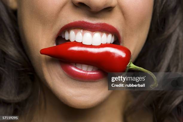 close-up of a young woman biting a red chili pepper - female eating chili bildbanksfoton och bilder