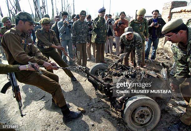 Indian policemen pull out the wreckage of a car blasted by suspected Kashmiri rebels targeting an Indian army convoy on the outskirts of Srinagar, 18...