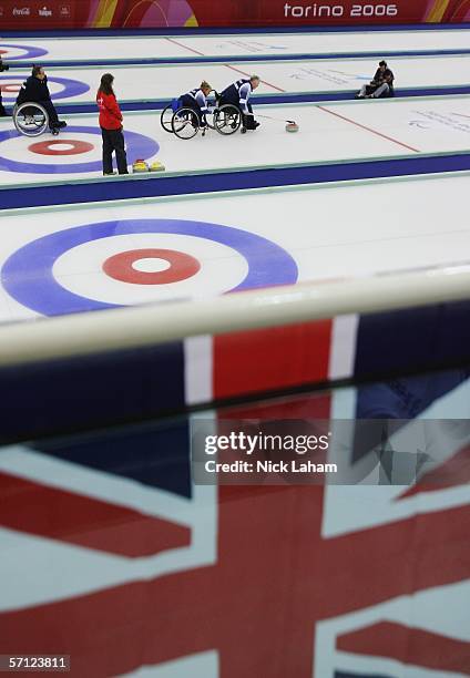 Angie Malone holds the chair of Great Britian team mate Frank Duffy while he releases a stone in the Wheelchair Curling Final between Great Britain...