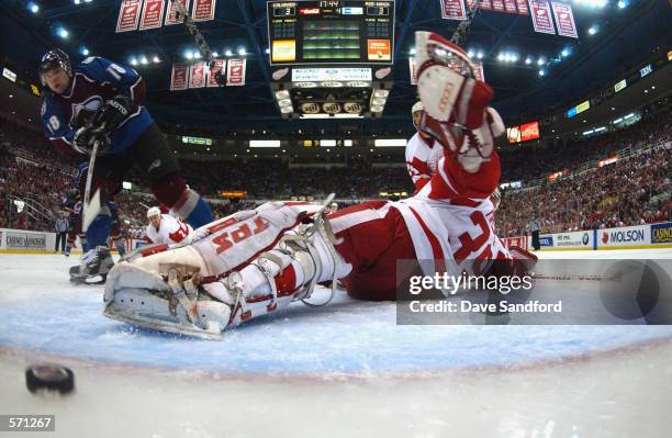 Chris Drury of the Colorado Avalanche dekes and puts a shot into the net past goaltender Dominik Hasek in the first overtime period of game two of...